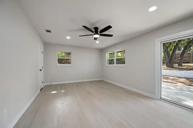 an empty room with a window and a ceiling fan