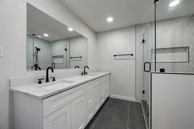 a bathroom with a double vanity sink a mirror and shower