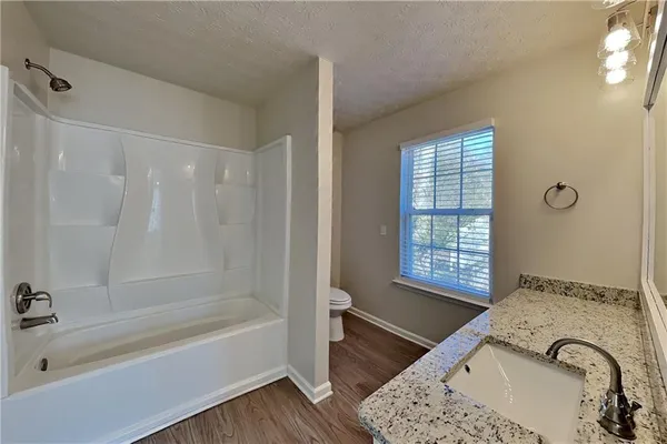 a bathroom with a granite countertop bathtub a sink and a shower