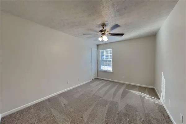 an empty room with windows and fan