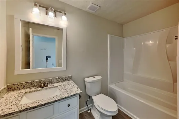 a bathroom with a granite countertop sink toilet mirror and bathtub