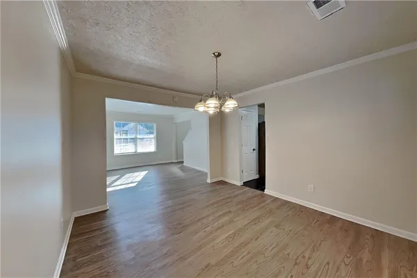 an empty room with wooden floor chandelier and entryway