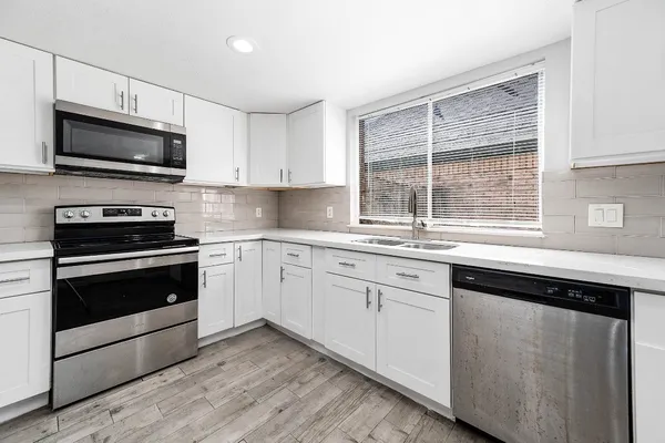 a kitchen with granite countertop white cabinets appliances a window and a sink