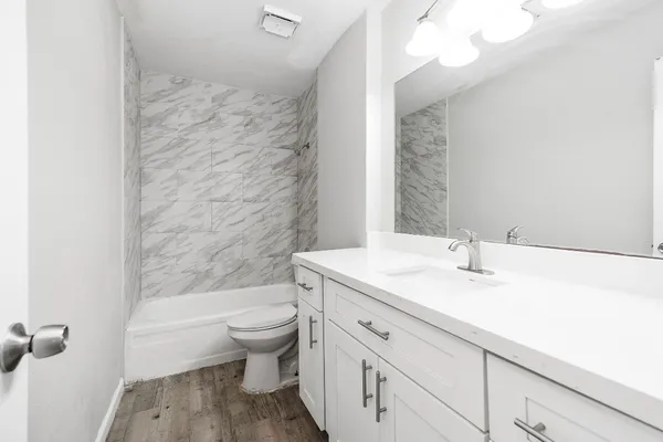a bathroom with a granite countertop sink a toilet and a bathtub