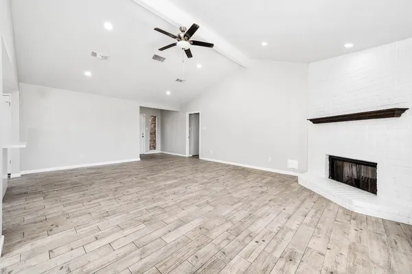 a view of an empty room with wooden floor and a fireplace