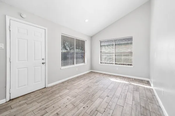 an empty room with wooden floor and windows