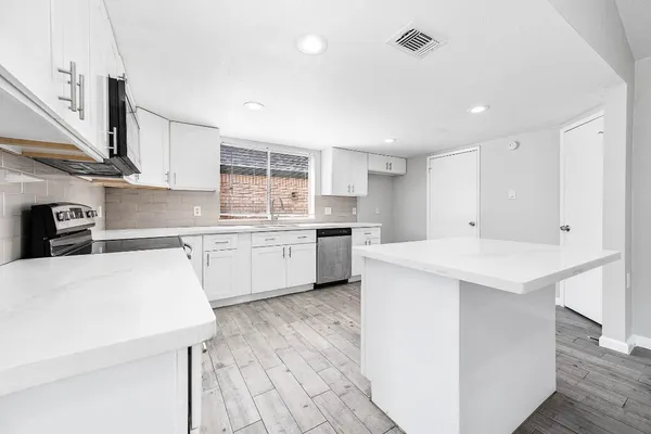 a kitchen with a sink a stove a refrigerator and white cabinets