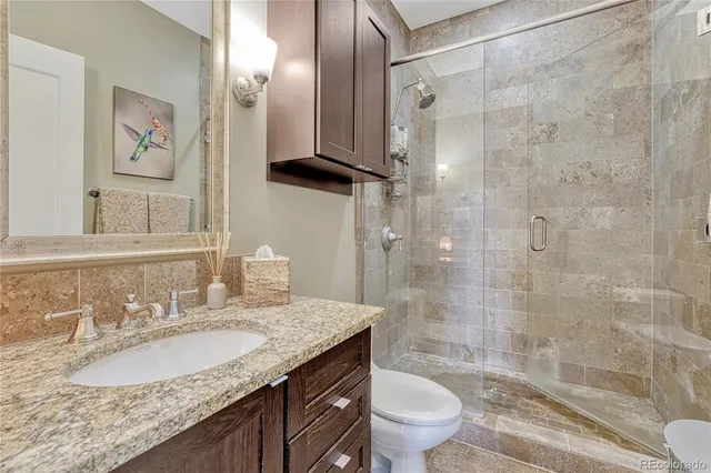 a bathroom with a granite countertop sink toilet and shower