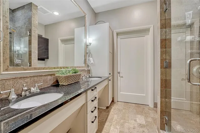 a bathroom with a granite countertop double vanity sink mirror and shower