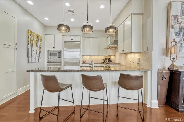 a kitchen with stainless steel appliances granite countertop a kitchen island a stove a cabinets a sink and a refrigerator