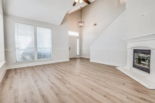 an empty room with wooden floor fireplace and windows