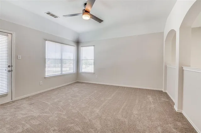 an empty room with windows and ceiling fan