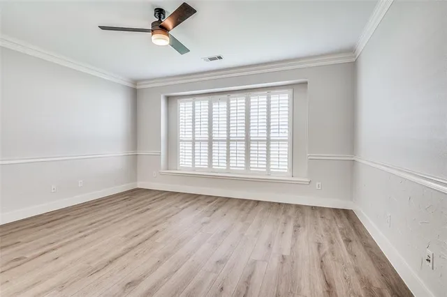 an empty room with wooden floor fan and windows