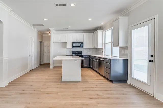 a large kitchen with kitchen island a sink a center island stainless steel appliances and a window
