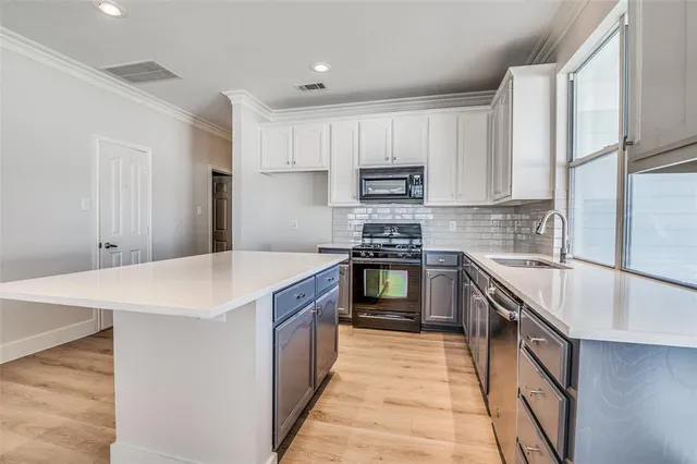 a kitchen with kitchen island white cabinets appliances and sink