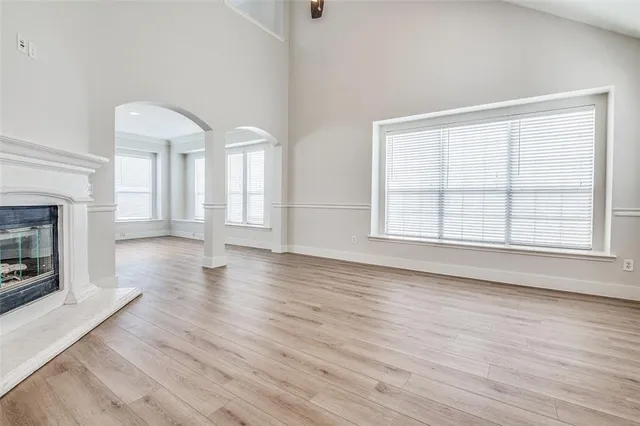 an empty room with wooden floor fireplace and windows