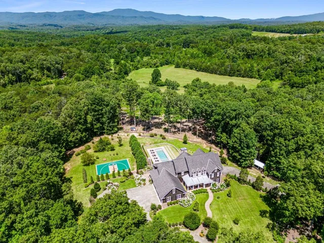 an aerial view of a house with swimming pool big yard and large trees