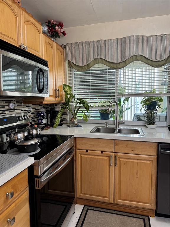 9400 Lime Bay Boulevard, Unit 112 Tamarac, FL 33321 - Photo 10 of 37 a kitchen with stainless steel appliances a sink a stove cabinets and a microwave