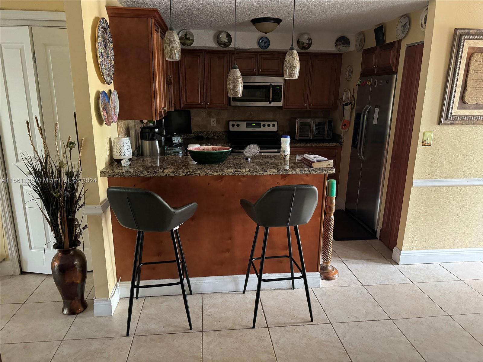 a kitchen with stainless steel appliances granite countertop table chairs and a refrigerator