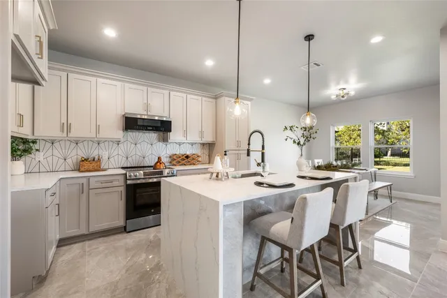 a kitchen with stainless steel appliances kitchen island granite countertop a sink a stove a kitchen island with chairs and white cabinets