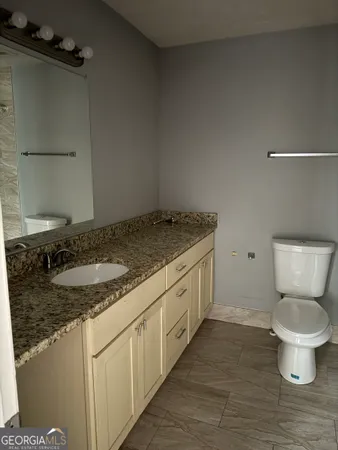 a bathroom with a granite countertop sink and a toilet