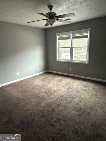 en empty room with windows and ceiling fan