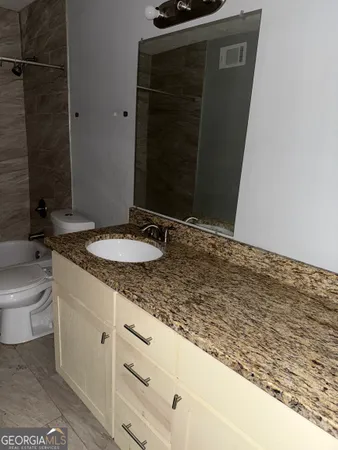 a bathroom with a granite countertop sink toilet and shower