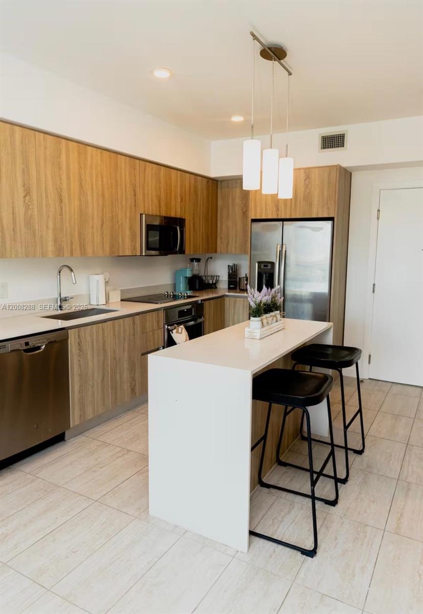 3900 Biscayne Boulevard, Unit S906 Miami, FL 33137 - Photo 6 of 17 a kitchen with a sink a microwave and cabinets