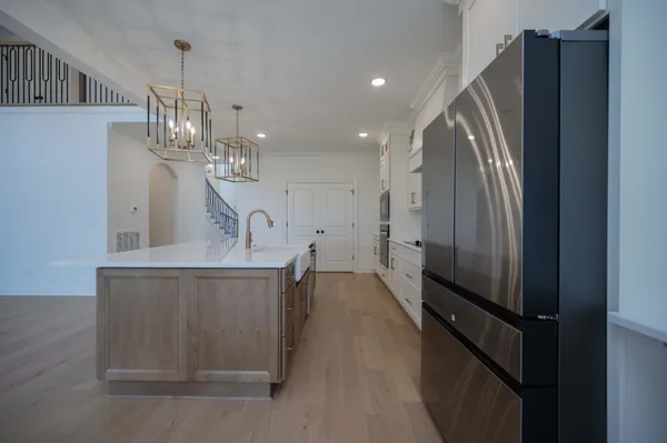 a kitchen with kitchen island a counter top space a sink a refrigerator and a stove