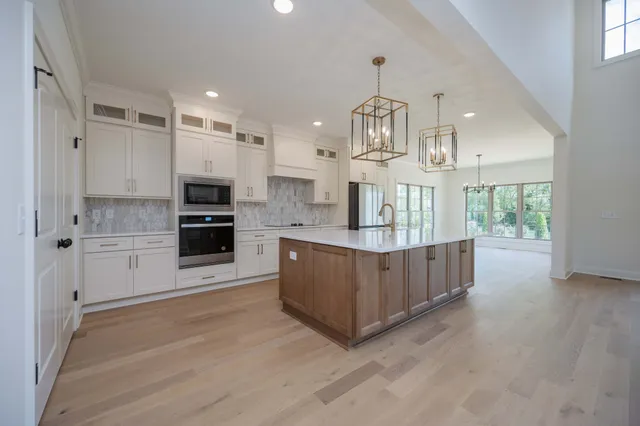 a large kitchen with kitchen island white cabinets and wooden floor