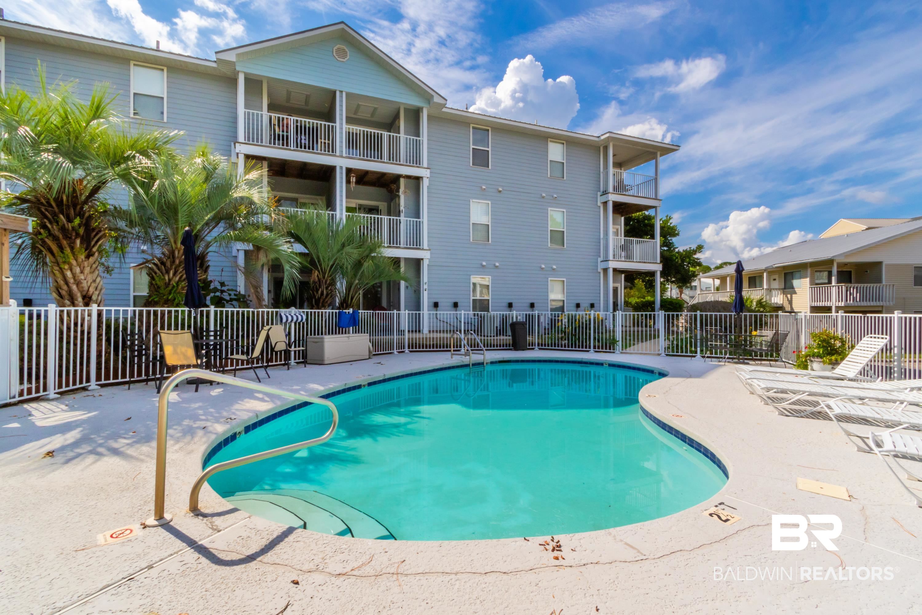 25957 Canal Road, Unit 208 Orange Beach, AL 36561 - Photo 1 of 28 Resort-style pool with integrated steps, surrounded by a white picket fence