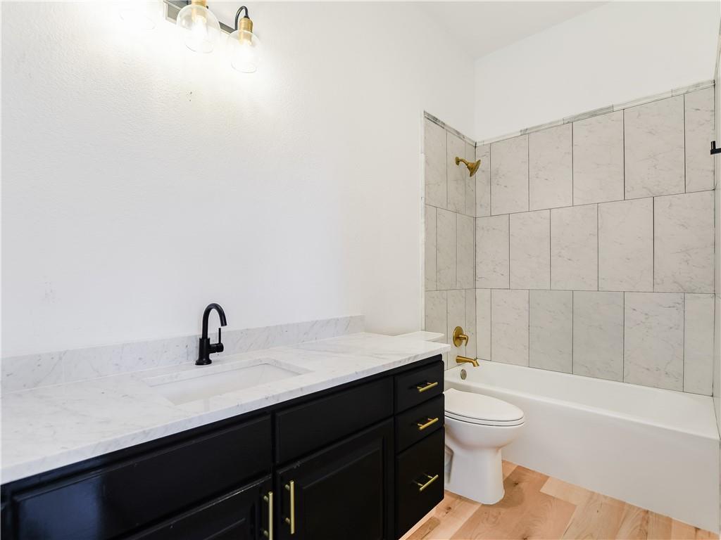 13301 Lone Rider Trail Bee Cave, TX 78738 - Photo 19 of 22 A well-appointed bathroom features a dark vanity with marble counters and a clean tub-shower combination with tiled walls.