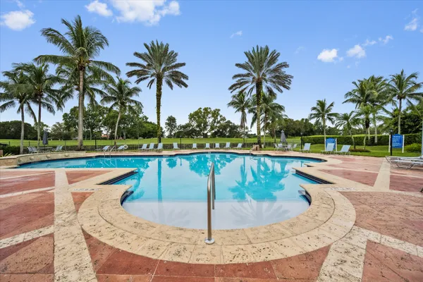 a view of a swimming pool with a yard and palm trees