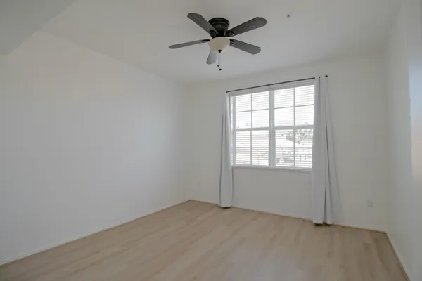 an empty room with a window and a fan