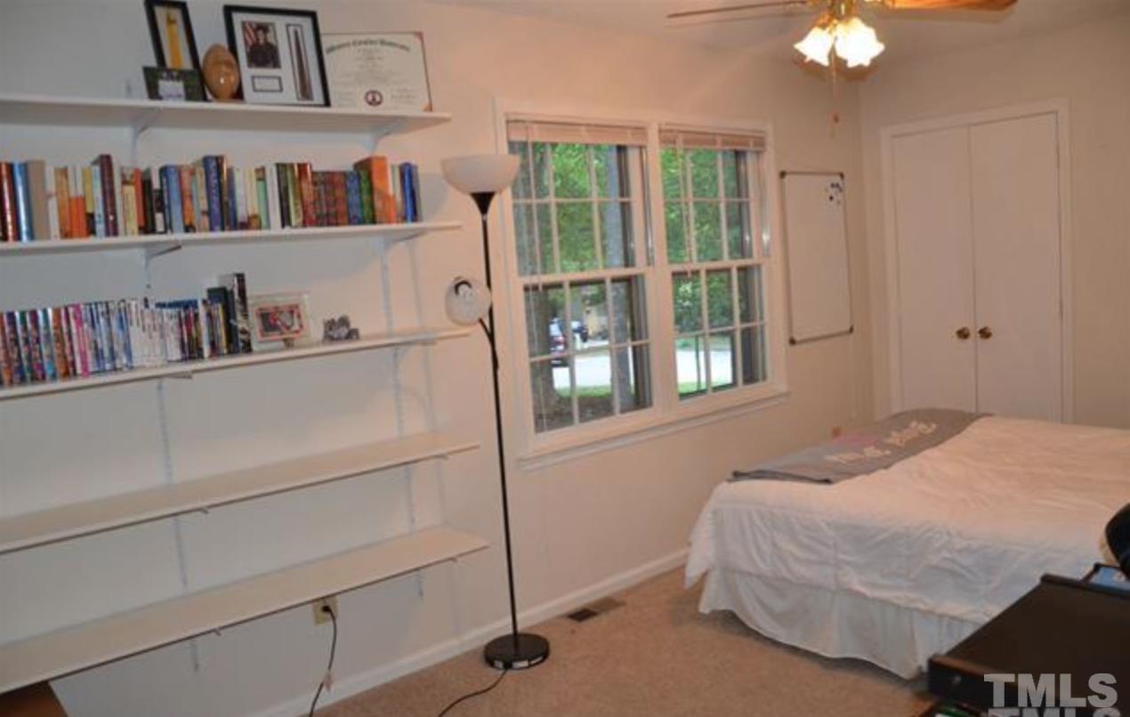 7809 Hemlock Court Raleigh, NC 27615 - Photo 11 of 16 a bedroom with a bed and a book shelf