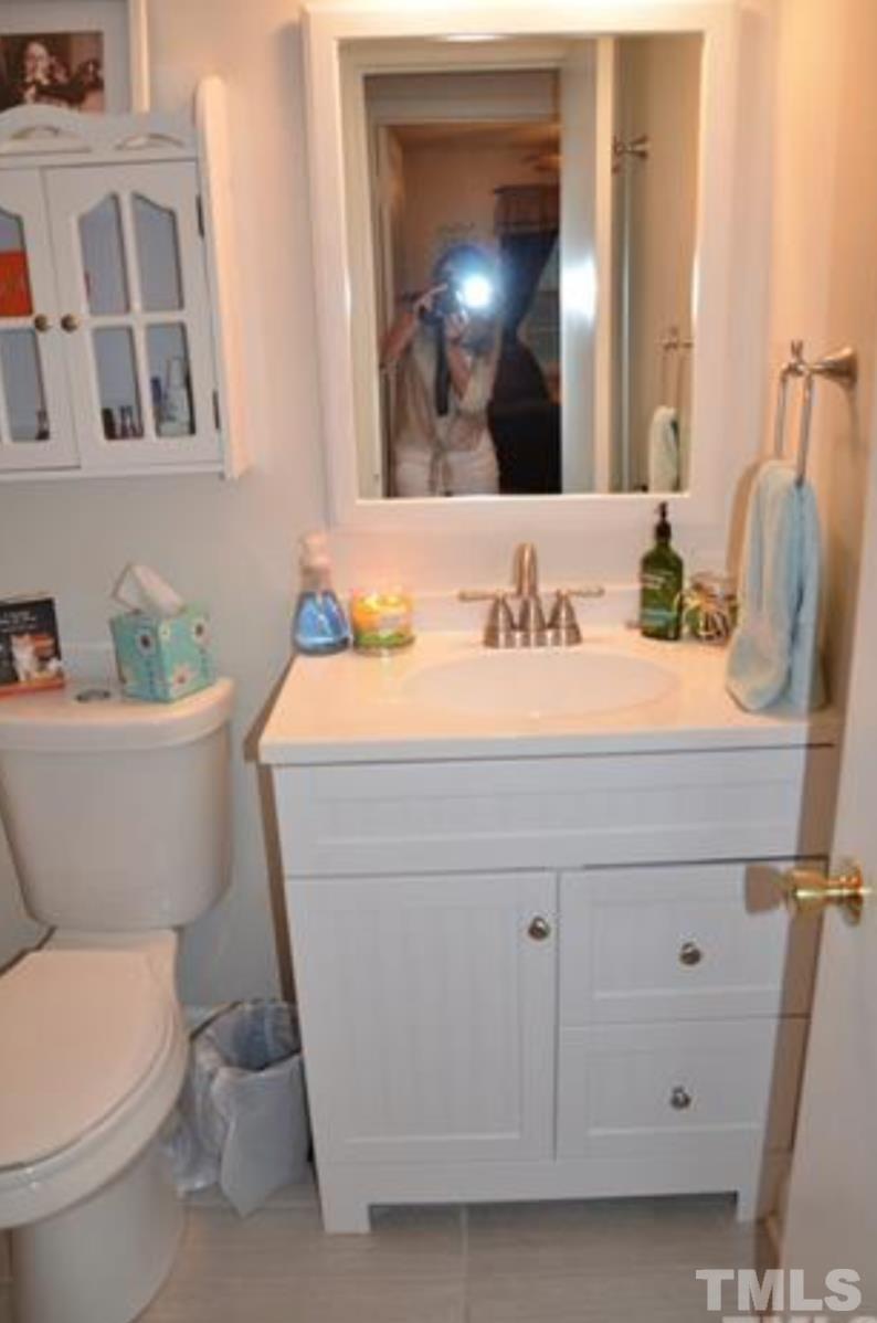 7809 Hemlock Court Raleigh, NC 27615 - Photo 13 of 16 a bathroom with a toilet a sink and a mirror