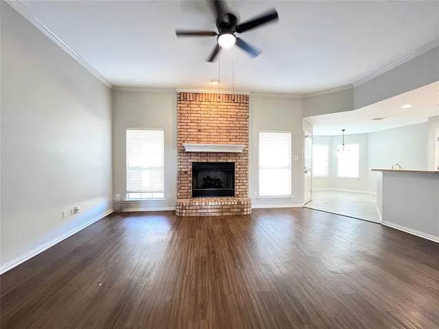an empty room with wooden floor fireplace and windows