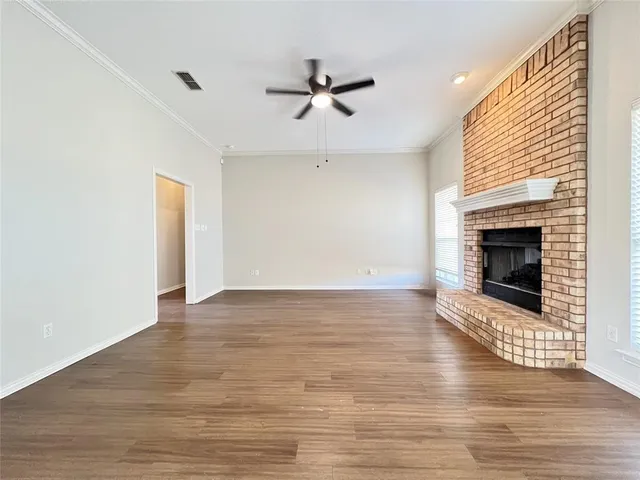 a view of an empty room with wooden floor fireplace and a window