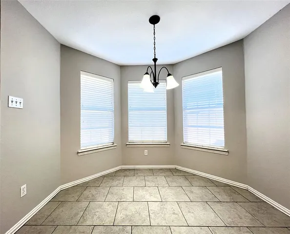 an empty room with windows and chandelier