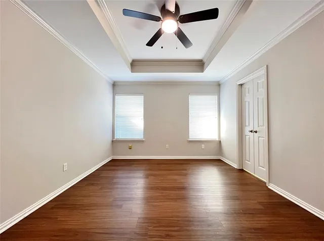 an empty room with wooden floor chandelier fan and windows