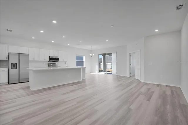 a view of kitchen with stainless steel appliances cabinets large window and wooden floor