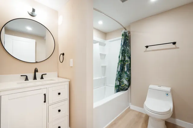 a bathroom with a toilet sink vanity tub and mirror