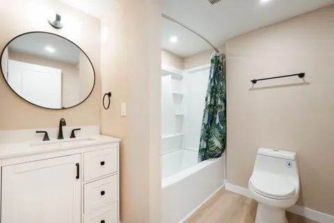a bathroom with a toilet sink vanity tub and mirror