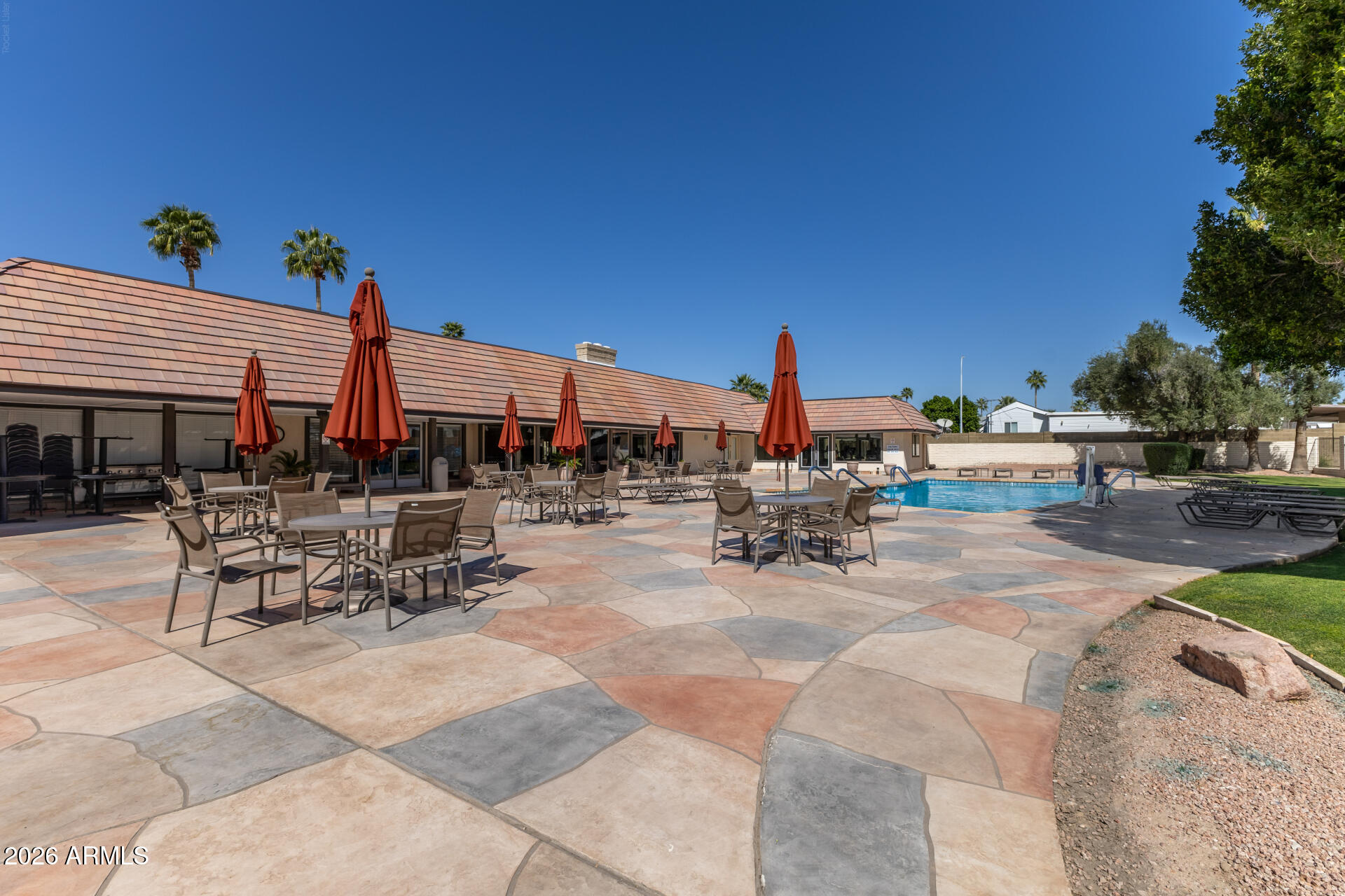 201 South Greenfield Road, Unit 254 Mesa, AZ 85206 - Photo 25 of 35 a view of a patio with dining table and chairs under an umbrella with potted plants