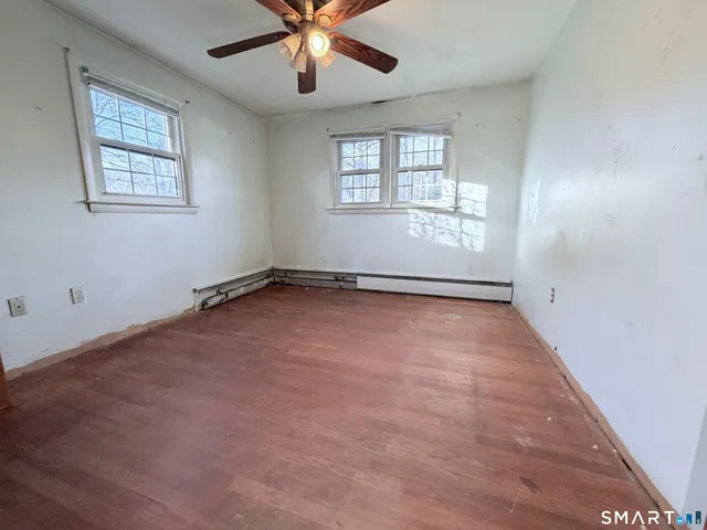 an empty room with windows and fan