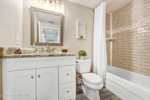 a bathroom with a granite countertop toilet a sink and a bathtub