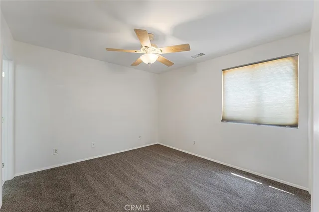 an empty room with a window and a fan