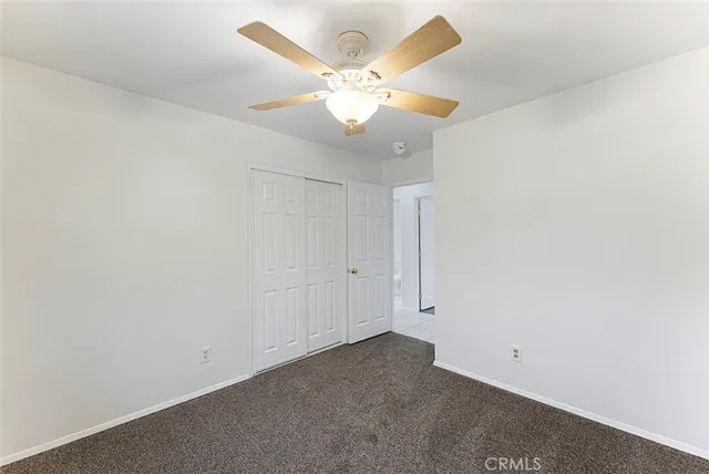 an empty room with a chandelier fan and windows