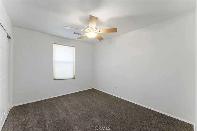 an empty room with a window and a fan