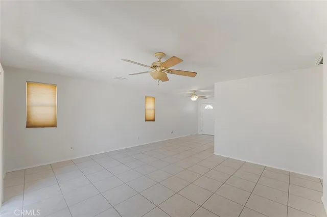 an empty room with ceiling fan and window